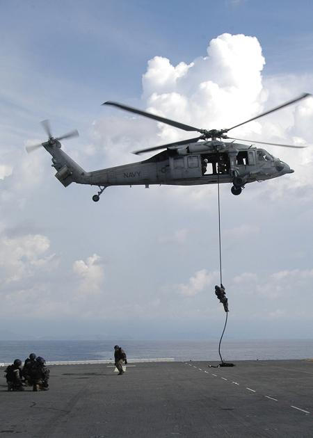 Une équipe de visite Français descend en rappel d'un hélicoptère SH-60 Seahawk sur le pont de l'USS Wasp