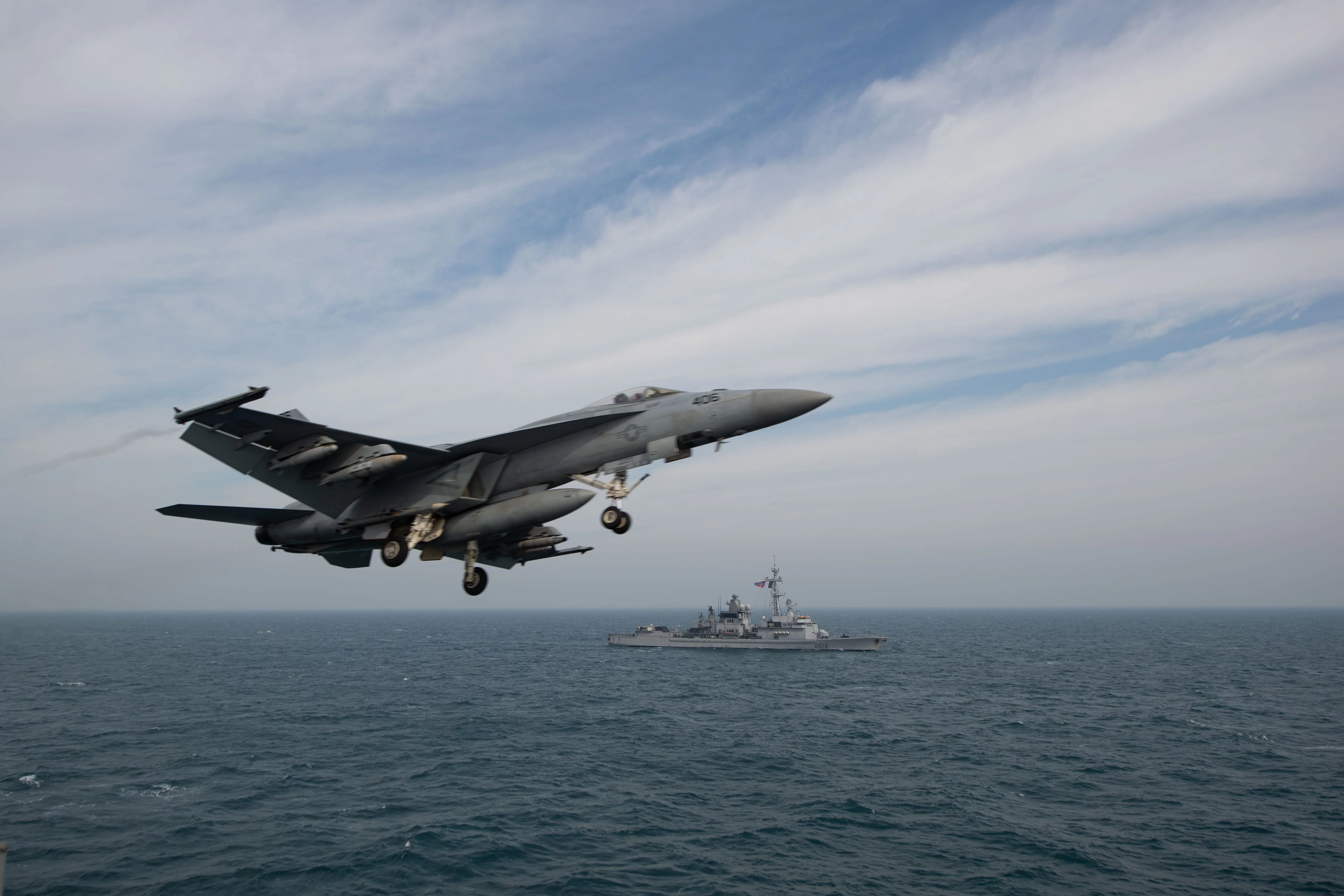 Un chasseur F-18 décole du porte-avions USS John C. Stennis devant la frégate Cassard
