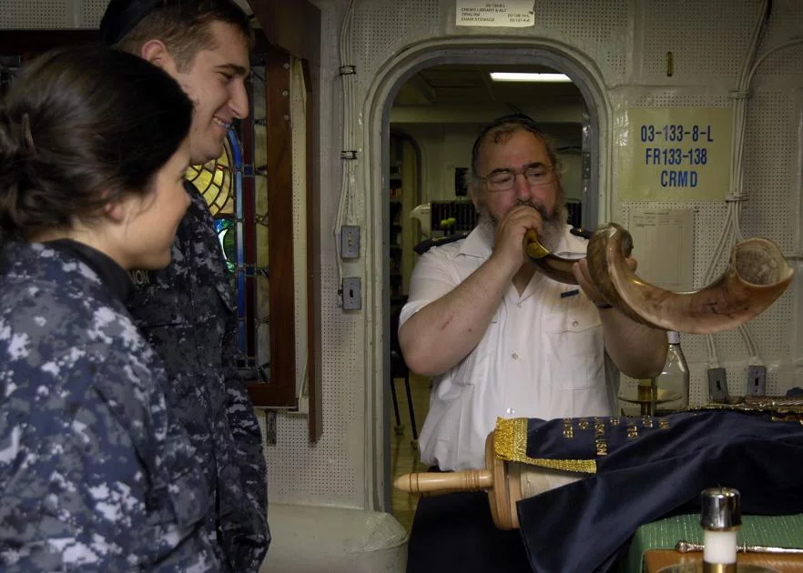 Meyer Malka, un rabbin militaire français, souffle dans une corne de cérémonie pendant un office célébré à bord du porte-avions USS Harry S. Truman