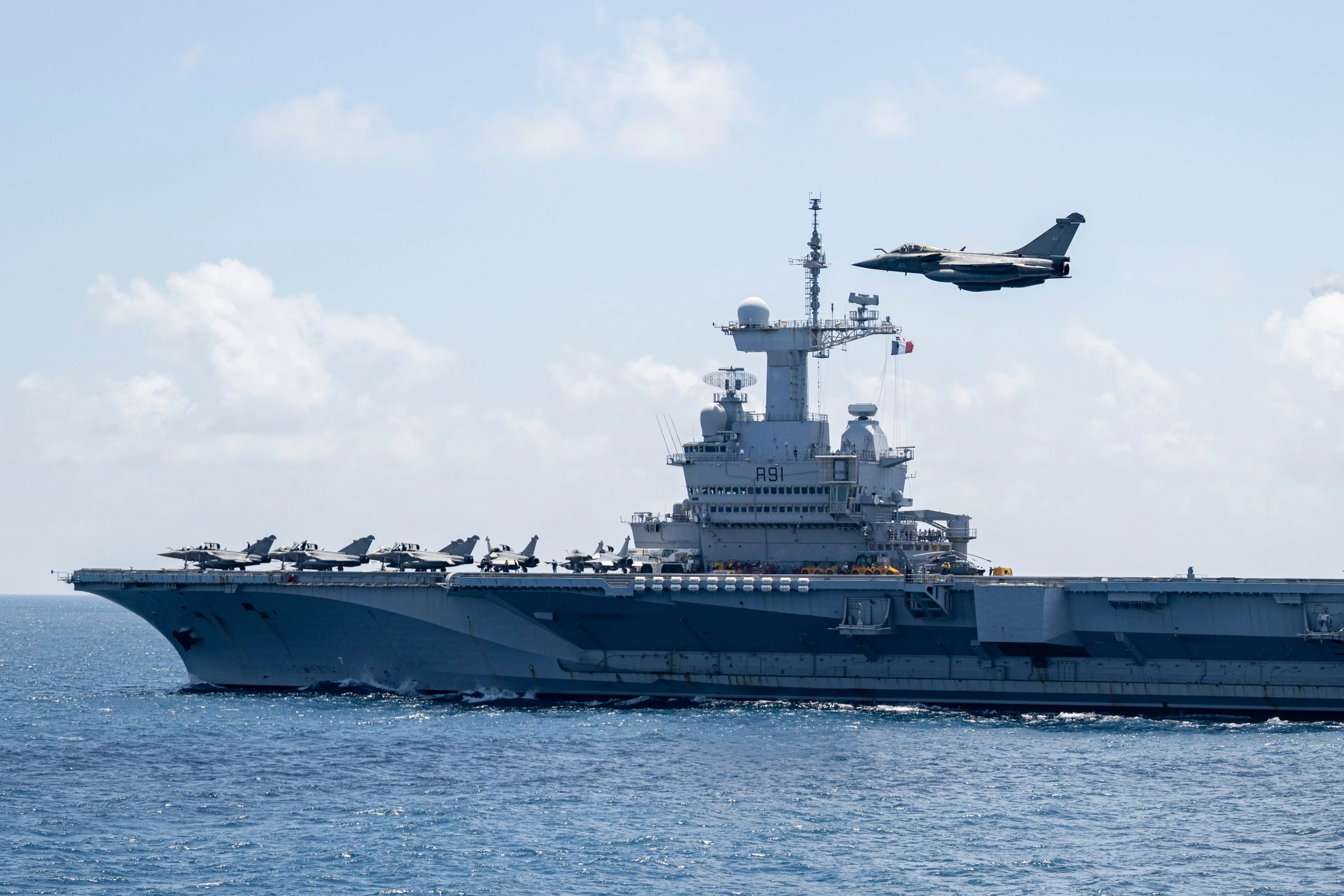Le porte-avions Charles de Gaulle survolé par un chasseur Rafale Marine