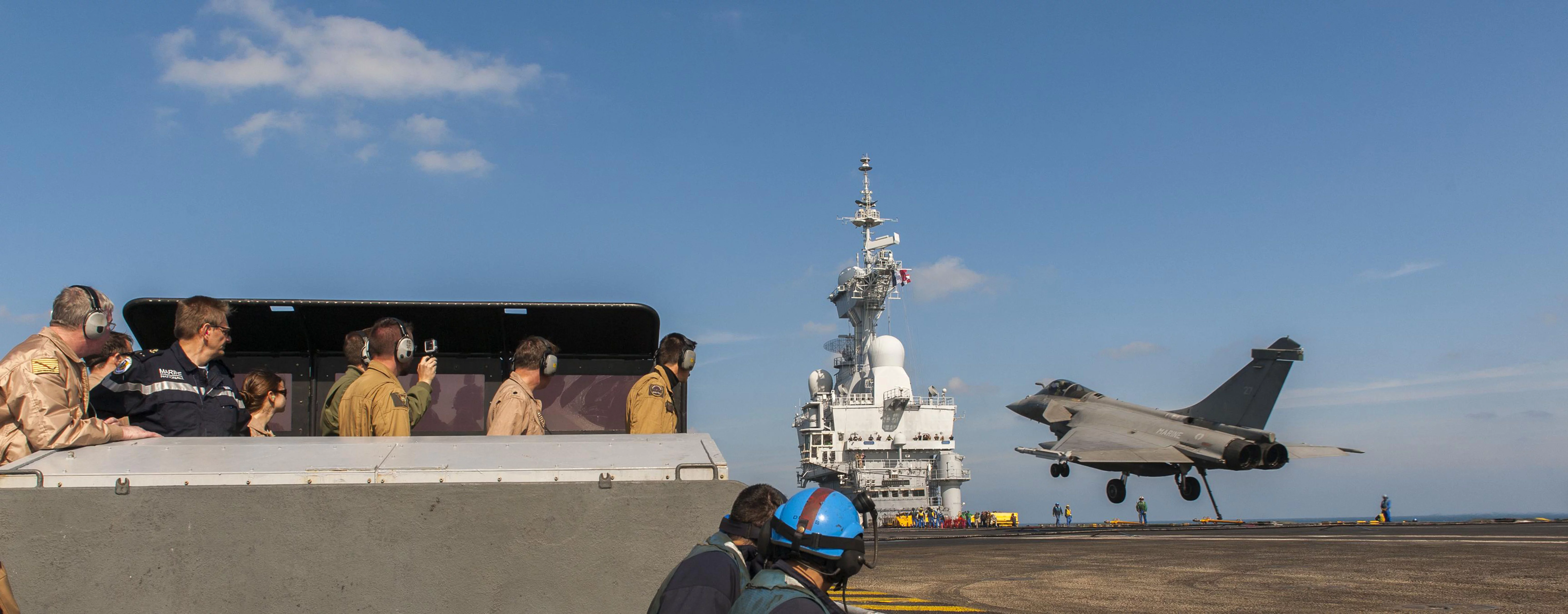 Le vice-amiral John Miller (à gauche) et le contre-amiral Eric Chaperon (2è à gauche) assistent à l'appontage d'un Rafale sur le Charles de Gaulle