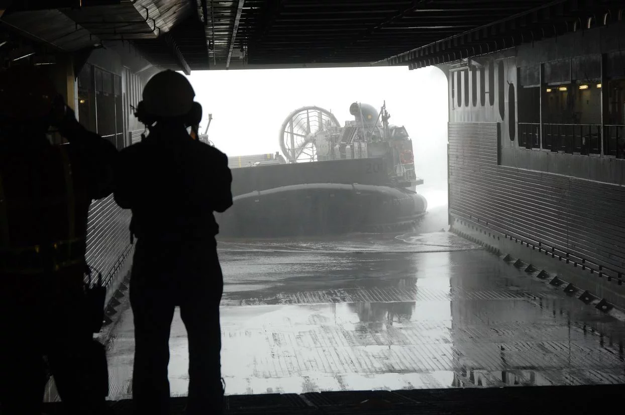 Un marin Français regarde un LCAC entrer dans le radier du Tonnerre