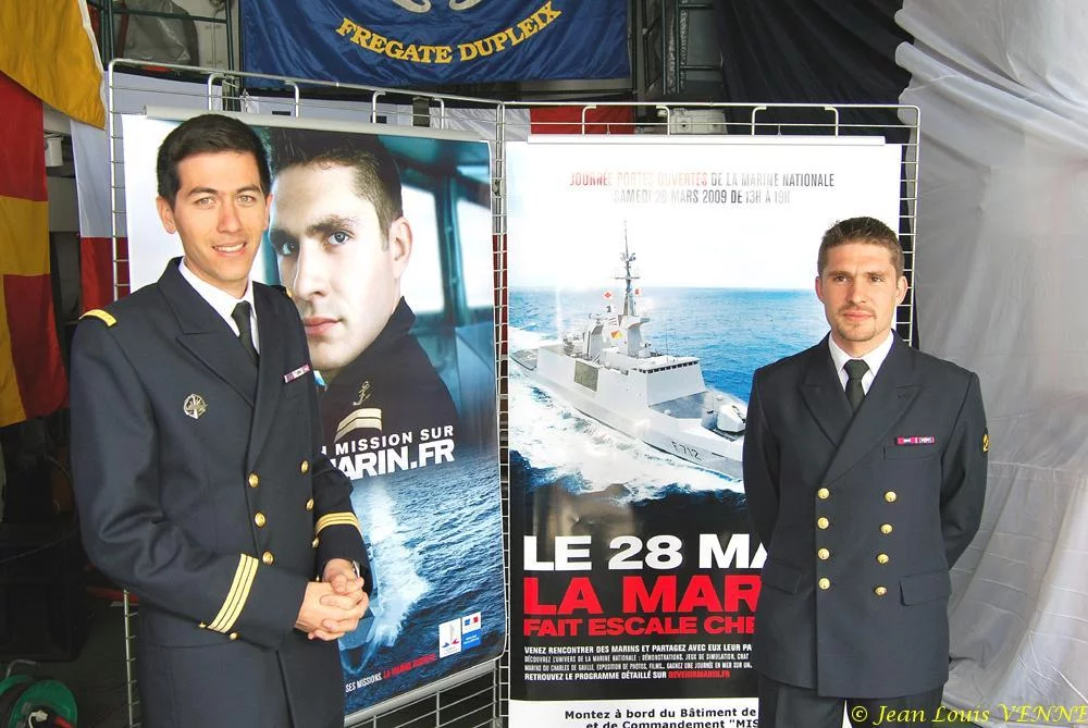 Les 2 marins devant les affiches de la campagne