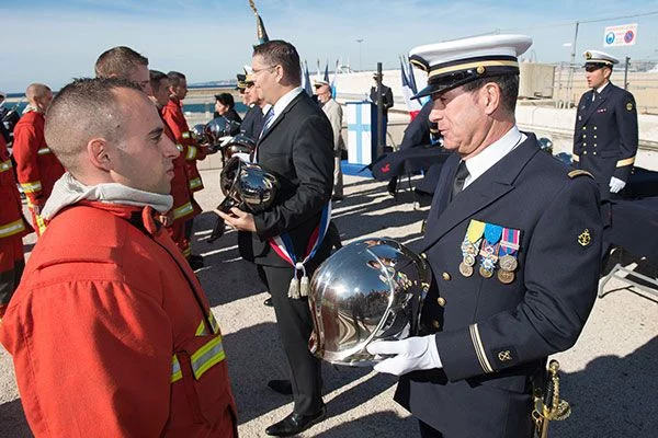 Le major Georges Zapian Zuasnabar, parrain de la promotion, remet son casque à un marin-pompier