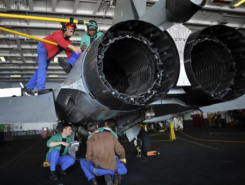 Une équipe de maintenance de la marine nationale, appartenant à l'escadrille 12F de Rafale, effectue un échange de moteur à bord du porte-avions américain USS Harry S. Truman