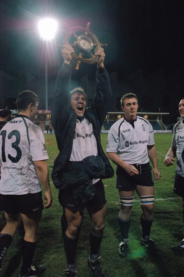 Un joueur de l'équipe de la Royal Navy brandit le trophée